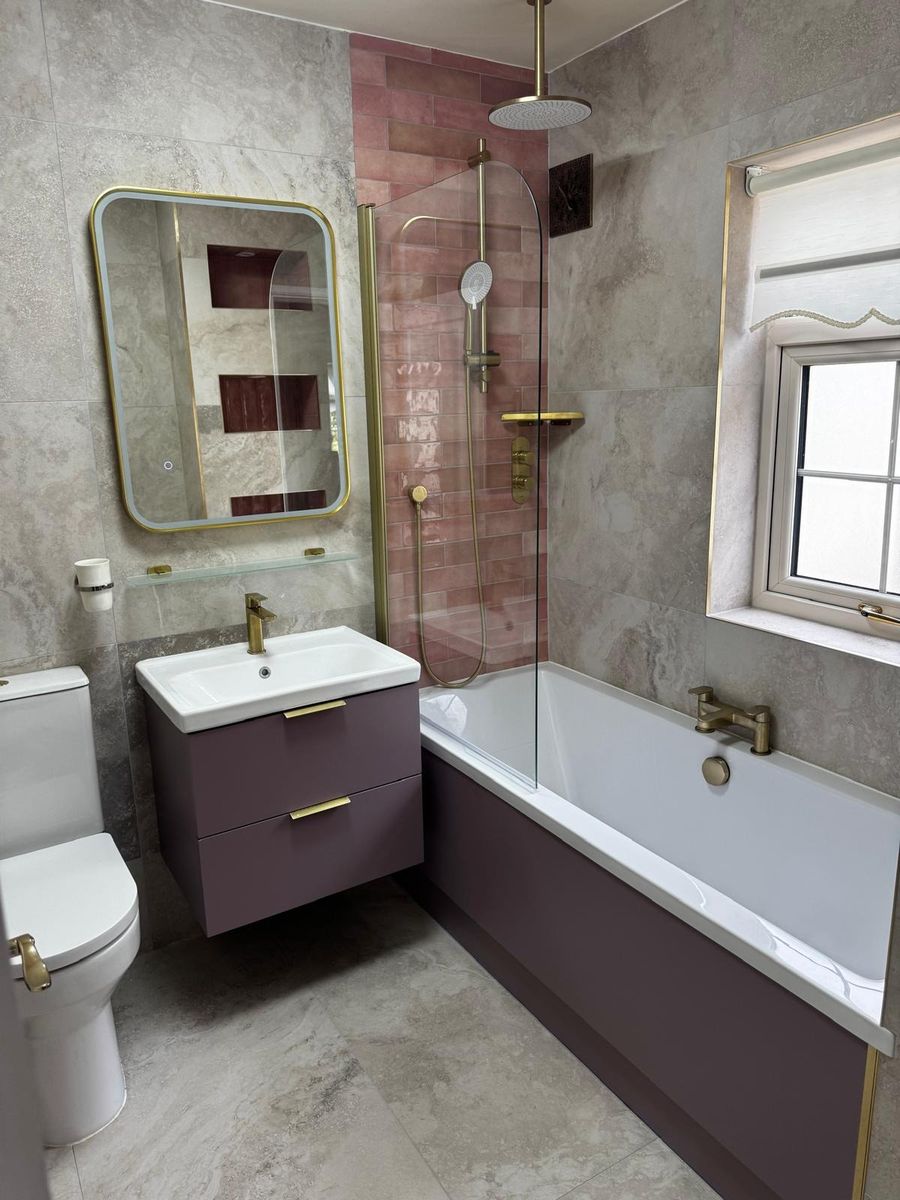 Bath with brass rain shower, glass screen and terracotta tiled recess