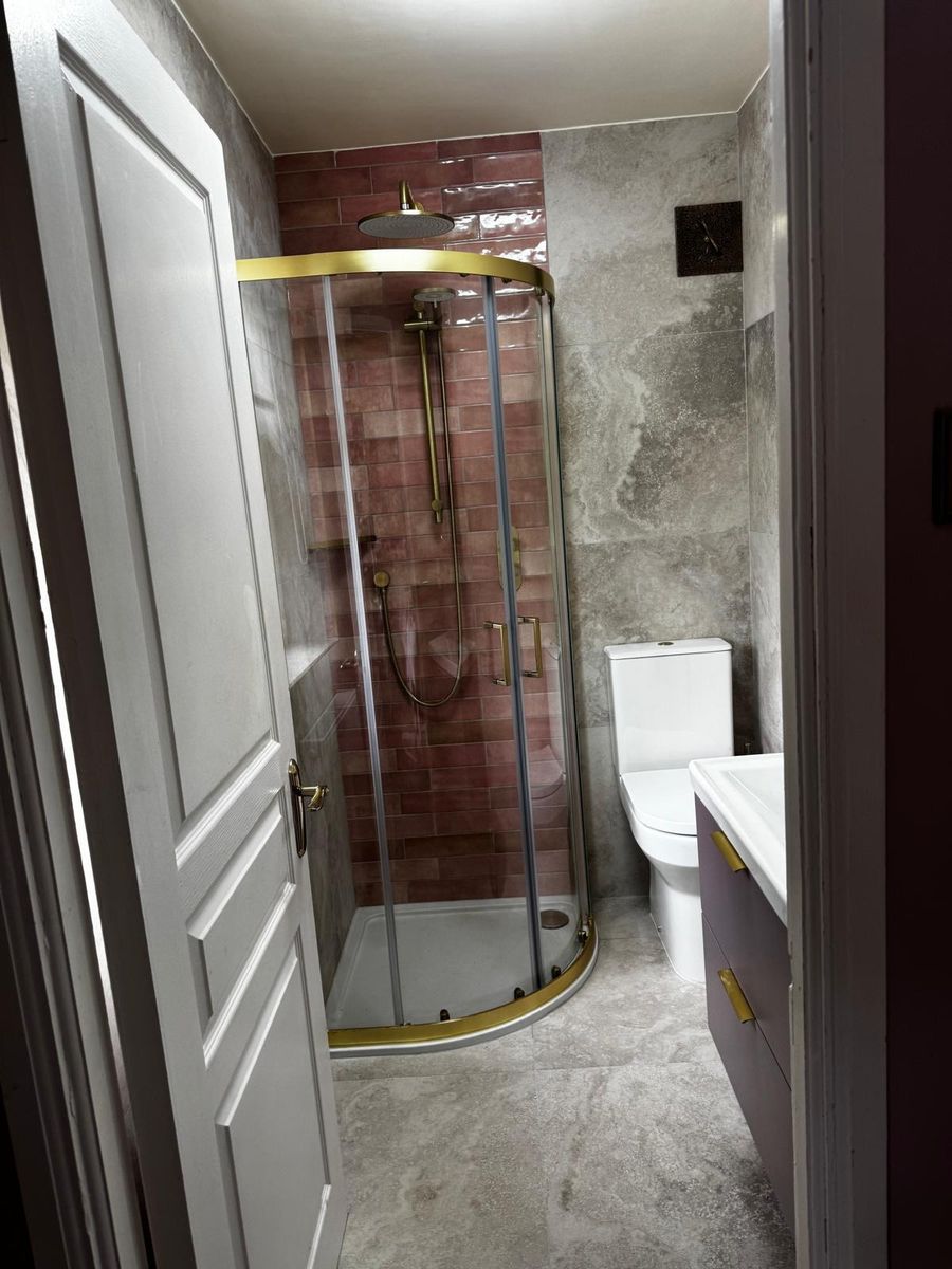 Quadrant shower enclosure with brass frame and tiled shower wall